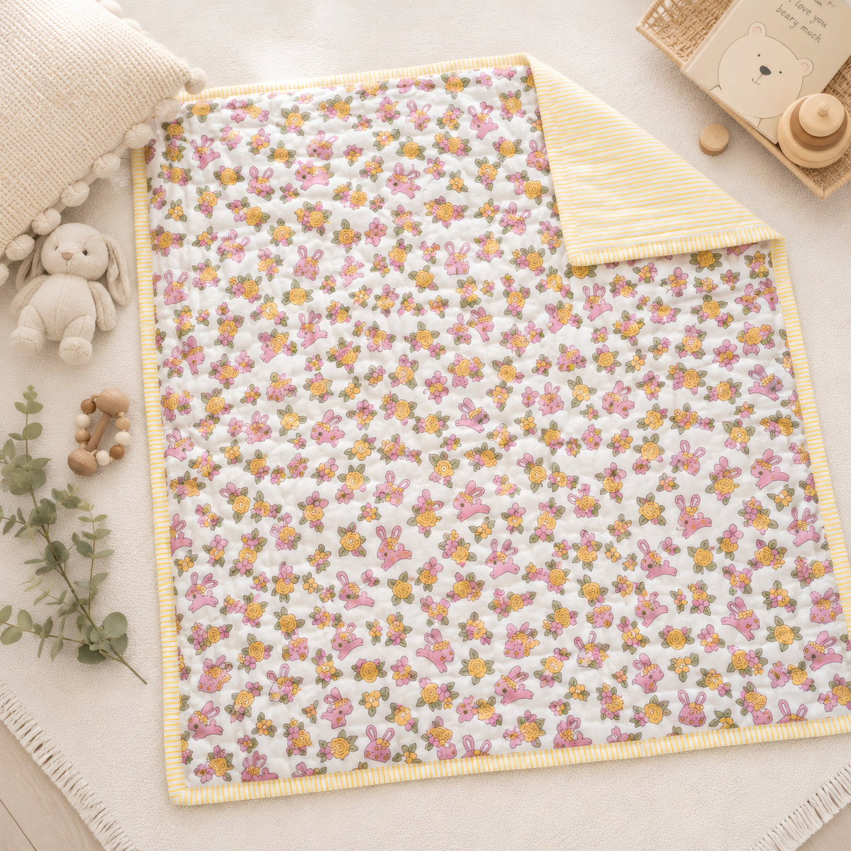 A hand block printed cotton baby quilt in a bunny and floral print